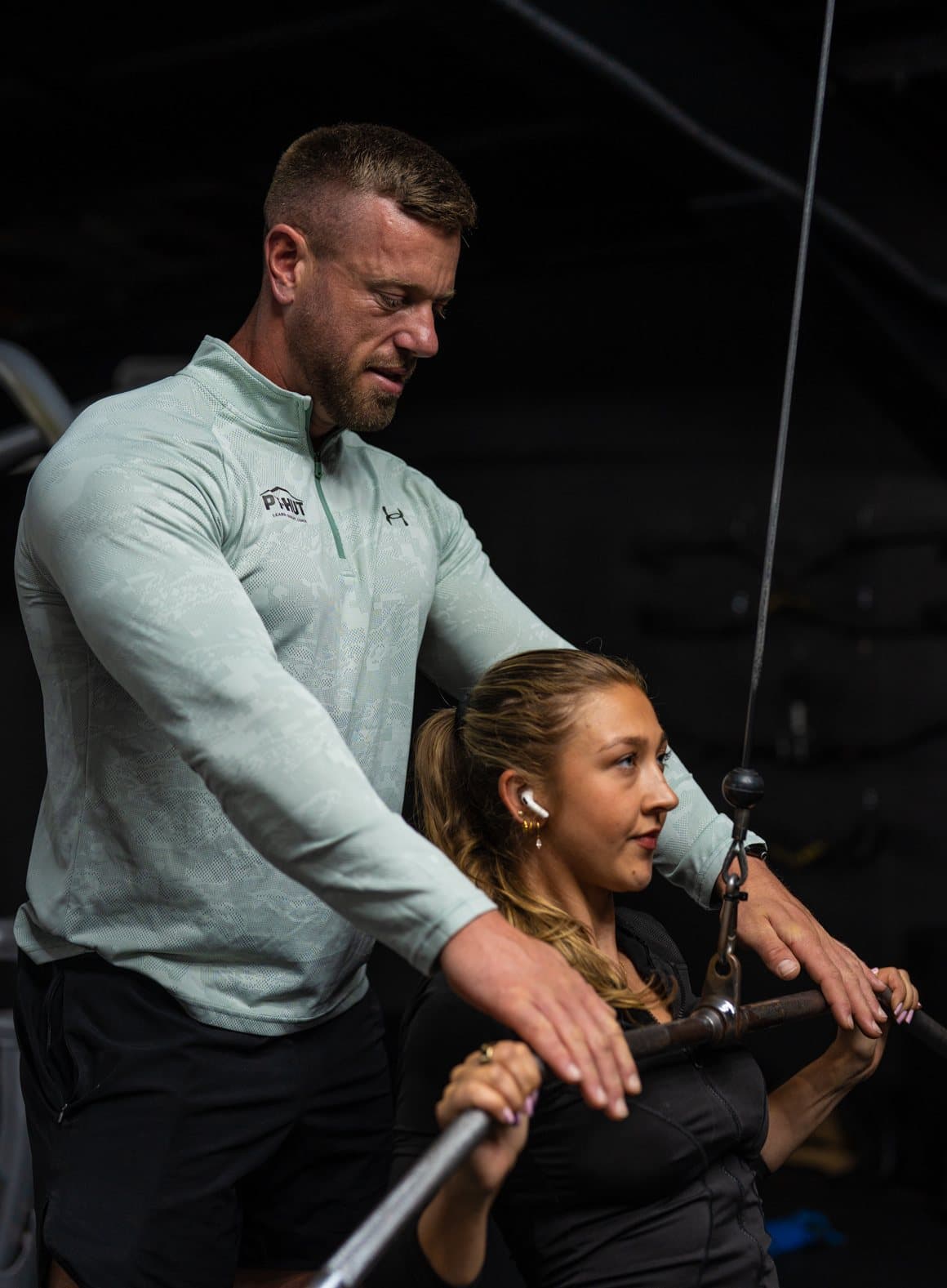 Clinton Coffey guiding a client's position on a lat pulldown during a coached session